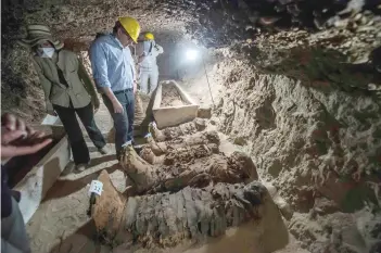  ?? — AFP ?? Egyptian Antiquitie­s Minister Khaled Al Anani (C) speaks to the media on Saturday in front of mummies following their discovery in catacombs in the Touna el Gabal district of the Minya province, in central Egypt.
