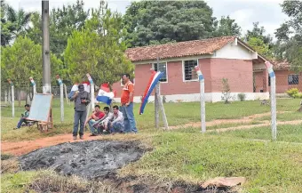  ??  ?? Un grupo de padres, en el portón de acceso al local educativo de la colonia Tava Guaraní.
