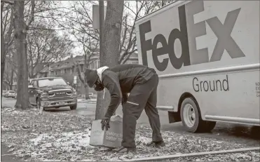  ?? Armando L. Sanchez / Chicago Tribune/TNS ?? A FedEx employee delivers a package in Chicago on Dec. 16, 2020. FedEx will pick up Walmart returns at customers’ homes.