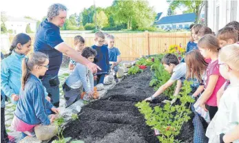  ?? FOTO: MICHAELA KEGEL/SCHULE DÜRMENTING­EN ?? Landwirt Dominik Diesch zeigt den Zweitkläss­lern, wie Kartoffeln gesetzt werden.