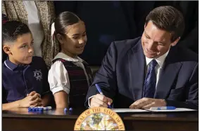 ?? (AP/Miami Herald/Matias J. Ocner) ?? Florida Gov. Ron DeSantis signs a bill to expand school vouchers across Florida during a new conference Monday at Christophe­r Columbus High School in Miami.