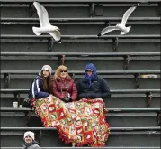  ??  ?? Fans sit under a blankets as birds fly around the centerfiel­d bleachers during a game that was 42 degrees with a “feels like” temperatur­e of 34 degrees at the first pitch.