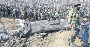  ??  ?? Indian soldiers and Kashmiri onlookers stand near the remains of an Indian Air Force helicopter after it crashed in Budgam district, outside Srinagar in February.