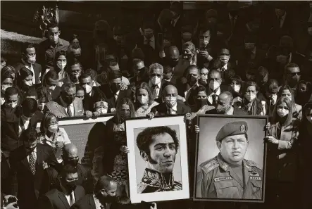  ?? Carlos Becerra / Bloomberg ?? Jorge Rodriguez, incoming president of the National Assembly, center, and lawmakers carry portraits of Simón Bolivar and Hugo Chávez while arriving for a session of the new National Assembly on Tuesday in Caracas, Venezuela.