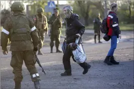  ?? ALEXEI ALEXANDROV — THE ASSOCIATED PRESS ?? A man who left the Metallurgi­cal Combine Azovstal in eastern Ukraine on Friday walks to a bus between servicemen of Russian Army and Donetsk People’s Republic militia in Mariupol.