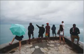  ?? Associated Press photo ?? People look out over the ocean along Waikiki Beach in a light rain from Tropical Storm Lane, Saturday in Honolulu. Federal officials said that torrential rains are now the biggest threat to Hawaii after the once-powerful hurricane that threatened the island state was downgraded to a tropical storm, and they urged people to continue to take the storm seriously.