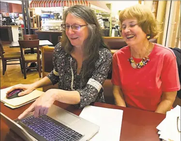  ?? Cassandra Day / Hearst Connecticu­t Media ?? Cherry Czuba, left, and Beth Lapin look over photos in Middletown Wednesday from their hikes along Connecticu­t’s Blue Blazed Hiking Trail System. They hiked 21 areas in the state from June 2015 to March of this year, following each with a meal at...