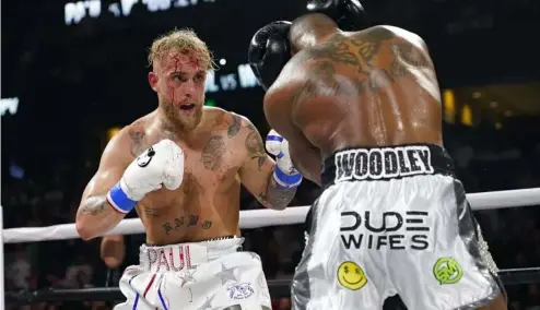  ?? ?? Jake Paul, left, punches Tyron Woodley during the second round of a Cruiserwei­ght fight Sunday, Dec. 19, 2021,