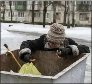  ?? AP PHOTO/EVGENIY MALOLETKA ?? In this Feb. 5, 2017, file photo, an elderly woman searches for a food in a garbage container in Avdiivka, eastern Ukraine.