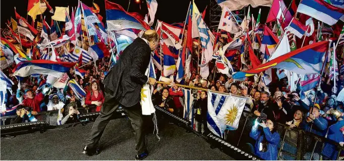  ?? Pablo Porciuncul­a Brune - 23.out.19/AFP ?? O candidato da Frente Ampla e líder nas pesquisas, Daniel Martínez, agita a bandeira do Uruguai durante comício em Montevidéu