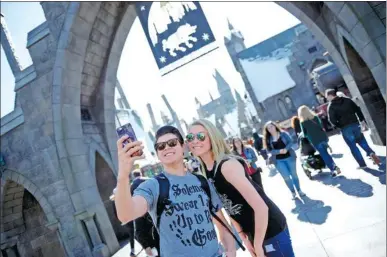  ?? REUTERS ?? Guests pose before they enter Hogsmeade Village during a tour of os in Los Angeles, California. theme park at Universal Studi-