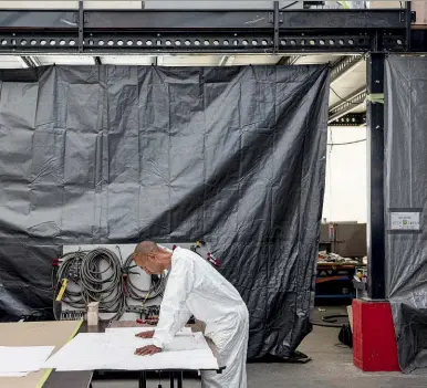  ??  ?? A sinistra, un boat builder controlla il progetto della barca. Sotto, membri del team nell’hangar barca. Nell’altra pagina, L’AC75 Luna Rossa nell’hangar della base