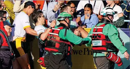  ?? ?? DRAMA: Cambridge’s exhausted stroke Matt Edge is carried from his boat by medics after victory in the Boat Race