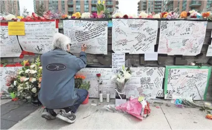  ?? LARS HAGBERG/GETTY IMAGES ?? A man writes a note at a makeshift memorial for victims of Monday’s van attack in Toronto that killed 10 people. Police arrested Alek Minassian after a confrontat­ion in which the suspect told officers to shoot him.