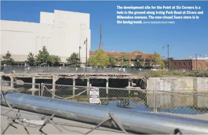  ?? DAVID ROEDER/SUN-TIMES ?? The developmen­t site for the Point at Six Corners is a hole in the ground along Irving Park Road at Cicero and Milwaukee avenues. The now-closed Sears store is in the background.