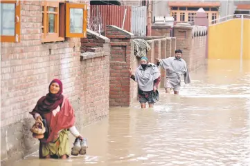  ??  ?? People wade through a flooded street after incessant rains in Srinagar.