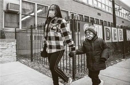  ?? Anthony Vazquez / Associated Press ?? Gina Lee walks with her son to drop him off for class outside of Suder Montessori Magnet Elementary School in Chicago.