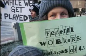  ?? AP PHOTO/ MICHAEL DWYER ?? Esther Anastasia holds a sign during a protest rally with government workers and their supporters in Boston on Friday.