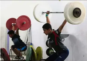  ??  ?? Big shoes to fill: Boys lifting weights while training at the local weightlift­ing club in the town of Badra. — AFP