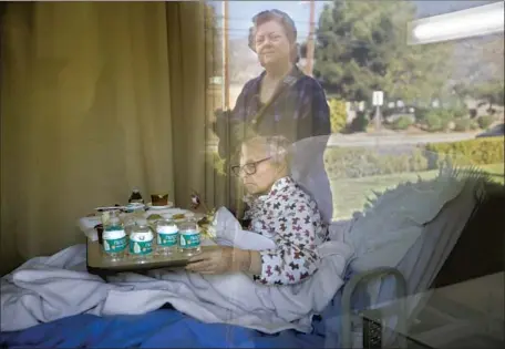  ?? Photog r aphs by Francine Orr Los Angeles Times ?? MARJORIE LEACH eats lunch at Mountain View Convalesce­nt Hospital. Her daughter Kathleen Hill visits her through a window.