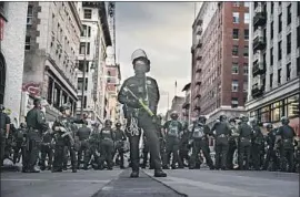  ?? Robert Gauthier Los Angeles Times ?? A LOS ANGELES police officer scans tall buildings along Broadway last week, when dozens of people were arrested for curfew violations after protests.