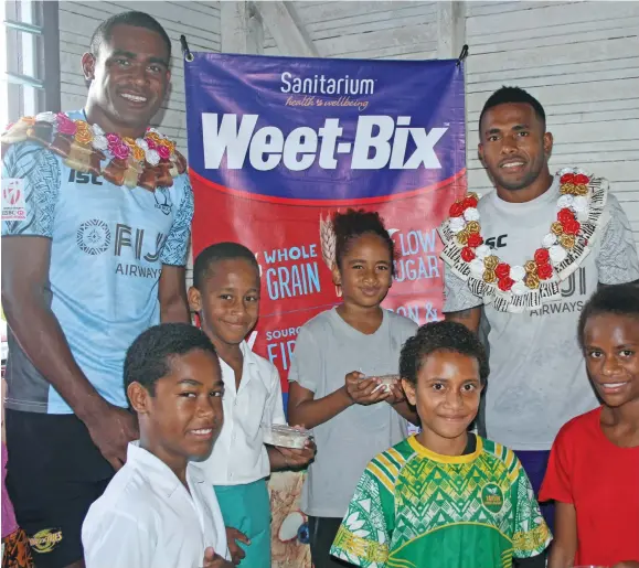  ??  ?? Fiji Rugby 7s stars Aminiasi Tuimaba (left) and Teri Tamani with some children of Kuku Village.