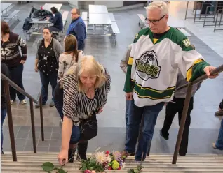  ?? Canadian Press photo ?? Humboldt mayor Rob Muench, in the Broncos jersey, along with other mourners lay down flower on the stairs that enter to Elgar Petersen Arena, home of the Humboldt Broncos, in Humboldt, Sask., on Saturday.