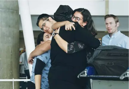  ?? (Carlo Allegri/Reuters) ?? PEOPLE HUG after arriving in advance of the incoming travel ban to the US at New York City’s John F. Kennedy airport on Thursday.