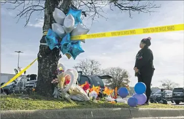  ?? MARY CHATKOVSKY Billy Schuerman Virginian-Pilot ?? places f lowers on a memorial outside the Chesapeake, Va., Walmart on Thursday.