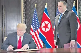  ??  ?? El presidente estadounid­ense Donald Trump firma el histórico acuerdo con Corea del Norte, ante la mirada del secretario de Estado Mike Pompeo (d). (AFP)