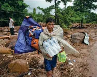  ?? JES AZNAR / GETTY IMAGES ?? Villagers wait to be evacuated near a damaged house and debris on Saturday in Attepeu, southeaste­rn Laos after a hydroelect­ric
dam collapsed on Monday.