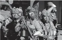  ?? [TED S. WARREN/THE ASSOCIATED PRESS] ?? Law enforcemen­t officers hold weapons as they face protesters Saturday near the Seattle Police East Precinct headquarte­rs. A large group of protesters marched there in support of Black Lives Matter and against police brutality and racial injustice.