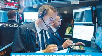  ??  ?? NEW YORK: Traders work after the opening bell at the New York Stock Exchange (NYSE) on Friday. — AFP