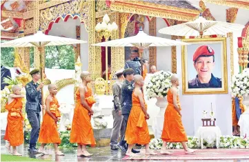  ??  ?? The rescued Thai boys and members of the ‘Wild Boars’ football team ordained as novice Buddhist monks walk in procession by the portrait of Kunan at the Wat Phra That Doi Tung temple in the Mae Sai district of Chiang Rai province. — AFP photo