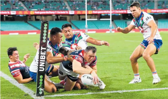  ?? Photo / Getty Images ?? Three Warriors defenders couldn’t stop Brett Morris of the Roosters sliding underneath them for a telling try.