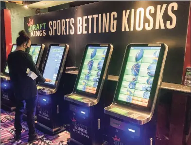  ?? Susan Haigh / Associated Press ?? In an image from Sept. 30, Zach Young, of New Haven, places a bet at one of the new sports wagering kiosks at Foxwoods Resort Casino in Mashantuck­et.