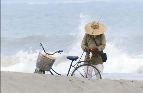  ??  ?? A man removes fish caught on his hook last Monday morning on the beach in Lingayen, Pangasinan. CESAR RAMIREZ