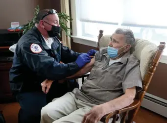  ?? NAncy lAnE / hErAld stAff filE ?? TAKING THE VACCINE TO YOU: Chris DiBona, chief clinical officer of Brewster Ambulance, vaccinates the homebound Raymond Mahan at his home in Leominster on March 16.