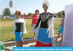  ??  ?? A woman looks at creations by local designers during an open air fashion show in Donetsk.