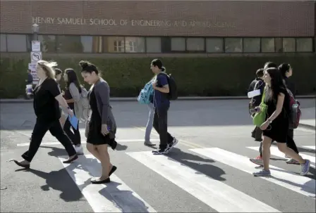  ??  ?? Students arriving to class walk past the engineerin­g department at the University of California, Los Angeles on Thursday. Classes at UCLA resumed Thursday for most of the school, except for the engineerin­g department, whose students and faculty will...