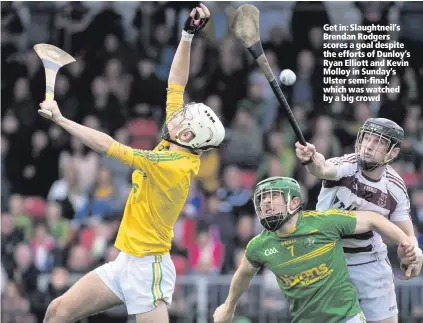  ??  ?? Get in: Slaughtnei­l’s Brendan Rodgers scores a goal despite the efforts of Dunloy’s Ryan Elliott and Kevin Molloy in Sunday’s Ulster semi-final, which was watched by a big crowd