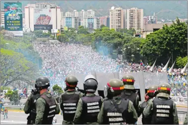  ?? FERNANDO LLANO/AP PHOTO ?? Bolivarian National Guards stand on a highway Wednesday above an anti-government protest against Venezuelan President Nicolas Maduro’s decree ordering a rewrite of the constituti­on in Caracas, Venezuela.