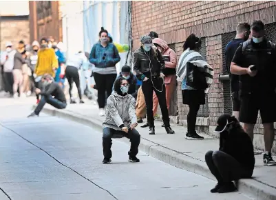  ?? NATHAN DENETTE THE CANADIAN PRESS ?? A woman stretches as hundreds of people wait in line in an alleyway for hours at a COVID-19 assessment centre at St. Michael’s Hospital in Toronto on Tuesday.