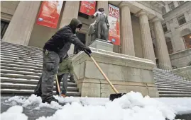  ?? RICHARD DREW/AP ?? A worker shovels snow from a sidewalk Tuesday in front of Federal Hall in New York’s Financial District. New York Gov. Andrew Cuomo declared a state of emergency Tuesday for all of the state’s 62 counties.