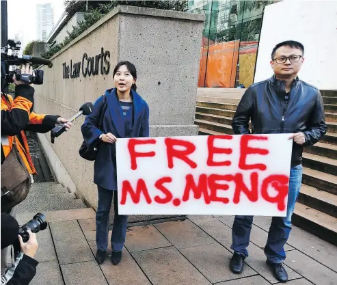  ?? JONATHAN HAYWARD / THE CANADIAN PRESS ?? Protesters hold a sign at a B.C. courthouse prior to the bail hearing for Meng Wanzhou on Monday.