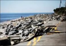  ?? TAILYR IRVINE/TAMPA BAY TIMES VIA AP ?? People walk around the destroyed portion of Alligator Drive, Friday in Alligator Point, Fla. The devastatio­n inflicted by Hurricane Michael came into focus with rows upon rows of homes found smashed to pieces, and rescue crews struggling to enter stricken areas in hopes of accounting for hundreds of people who may have stayed behind.