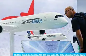  ?? —AFP ?? BEIJING: A visitor looks at an Airbus A350-1000 plane model at the Beijing Internatio­nal Aviation Expo in Beijing yesterday.