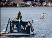  ?? BEN GARVER/THE BERKSHIRE EAGLE VIA AP ?? IN THIS DEC. 24, 2015, FILE PHOTO, a man jumps into Pontoosuc Lake in Pittsfield, Mass. The New England lake is typically frozen in December, but unusually warm temperatur­es have kept the water open. On Thursday, the National Weather Service forecasted a warmer than normal 2018-2019 winter for the northern and western three-quarters of the U.S.