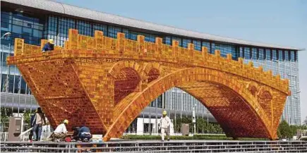  ??  ?? Workers working on a ‘Golden Bridge of Silk Road’ structure outside the National Convention Centre in Beijing, where world leaders are set to attend a summit this month to discuss China President Xi Jinping’s One Belt, One Road initiative.