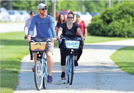  ?? MIKE DE SISTI / MILWAUKEE JOURNAL SENTINEL ?? Casimer Rosiecki (left) and his wife, Juliana Rosiecki, visiting from Pensacola, Fla., ride Bublr Bikes along North Lincoln Memorial Drive near Veterans Park along Lake Michigan in Milwaukee.